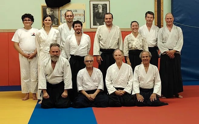 Photo de rentrée : quatorze pratiquants et enseignants du dojo posent devant les portraits du fondateur et de Tamura Sensei